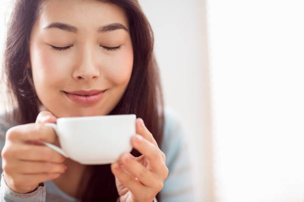 istock Asian woman relaxing on couch with coffee 670019662