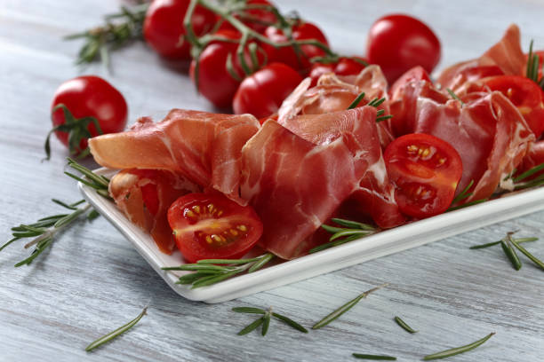 istock Prosciutto with  rosemary and tomato on a wooden table 670019910