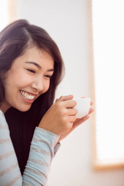 istock Asian woman relaxing on couch with coffee 670019960