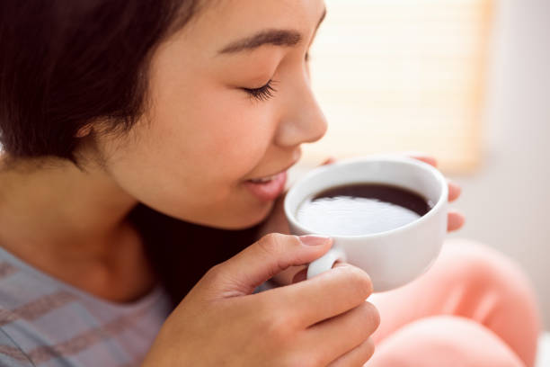 istock Asian woman relaxing on couch with coffee 670022294