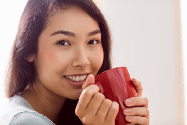 istock Asian woman relaxing on couch with coffee 670022684
