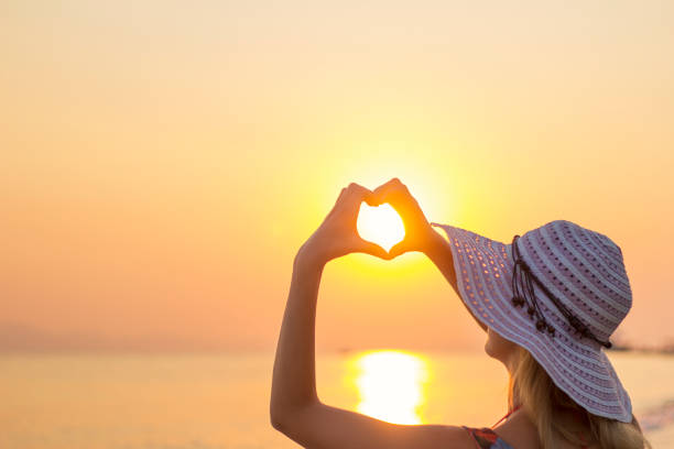 istock Girl holding hands in heart shape at beach 670022820