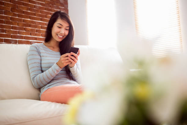 istock Asian woman reading text on couch 670023058