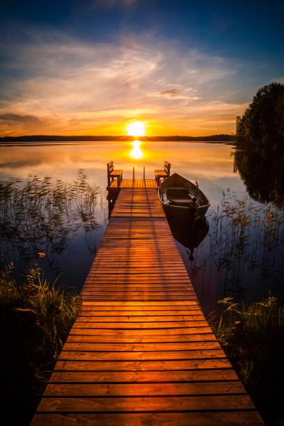 puesta de sol sobre el muelle de pesca en el lago en finlandia - wood chair outdoors rural scene fotografías e imágenes de stock