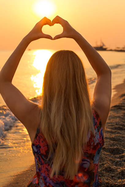 istock Female at the beach making a heart symbol 670032896