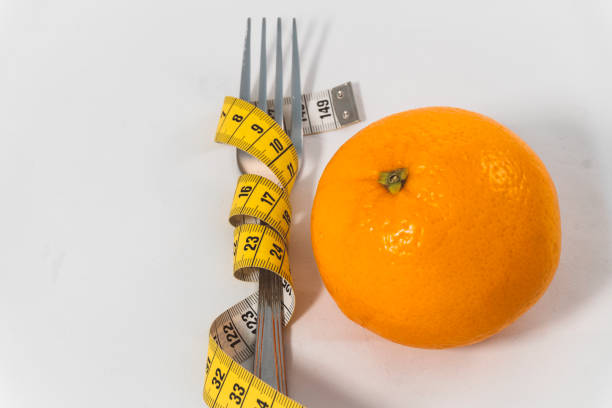 gabel, messung von band und orange - healthy eating fork tape measure still life stock-fotos und bilder