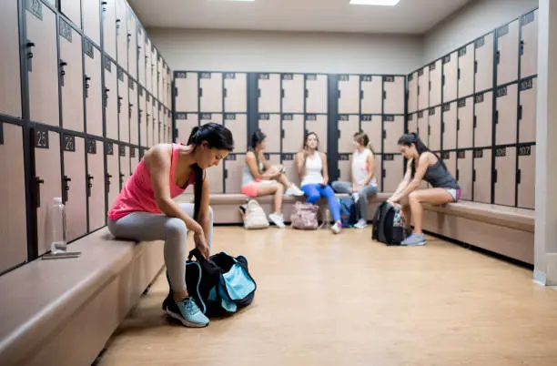 Women a the gym changing in the dressing room and putting their things in the lockers - healthy lifestyle concepts