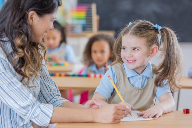 istock Confident schoolgirl talks with teacher 670045230