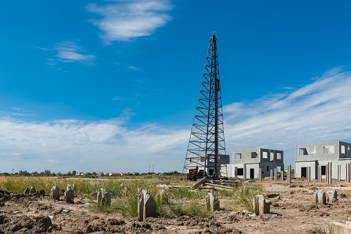 construction site with pile-driver working and precast housing on construction progress