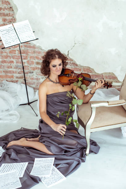 istock beautiful woman playing the violin bow rose 670050874