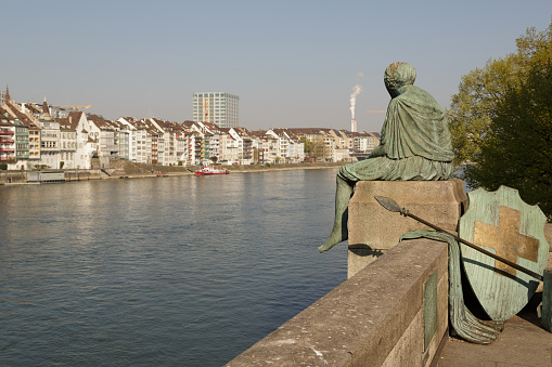 A photograph of the Helvetia staue on the Rhine river in Basel, Switzerland, taken on a sunny day in spring.