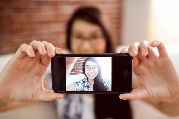 istock Asian woman on the couch taking selfie 670069134