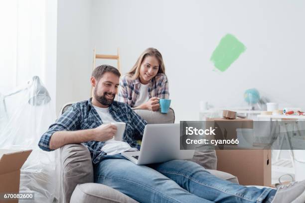 Couple Relaxing During Home Renovation Stock Photo - Download Image Now - Moving House, Renovation, Computer