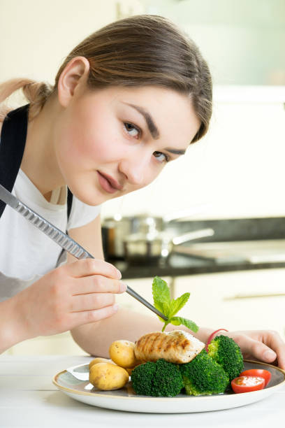 istock female chef garnish chicken vegetable dish kitchen 670085080