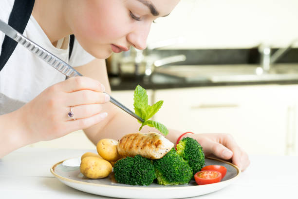 istock female chef garnish chicken vegetable dish kitchen 670090646