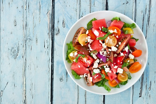 Watermelon and mixed tomato salad with feta cheese, above view on rustic blue wood