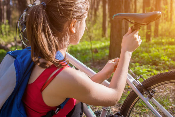 Young woman adjusting a saddle on her bicycle stock photo