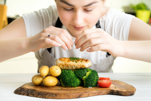 istock female chef garnish chicken vegetable dish kitchen 670096472