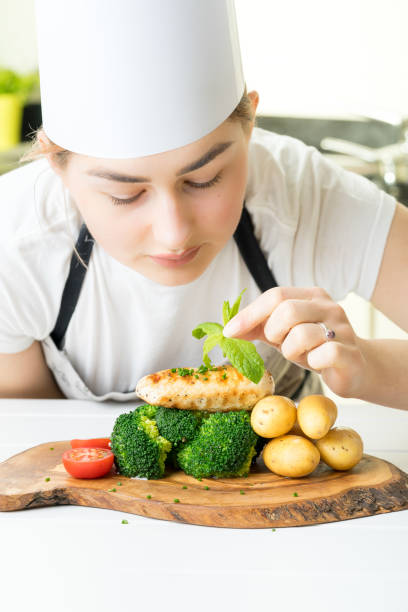 istock female chef garnish chicken vegetable dish kitchen 670102382