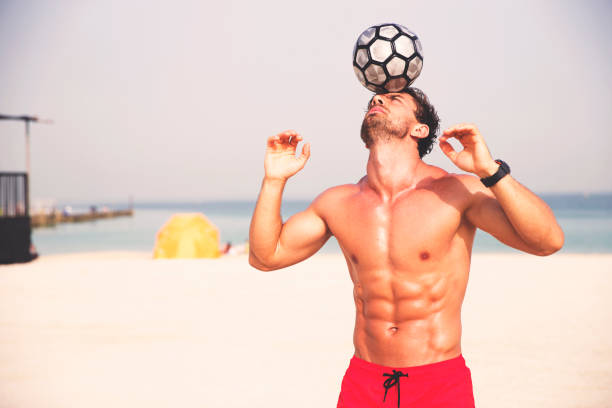 istock Man playing with a football at the beach 670106382