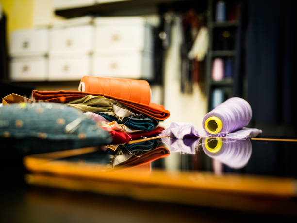 istock Bobbins, pieces of silk and touchpad on the table in tailor's workshop 670126614
