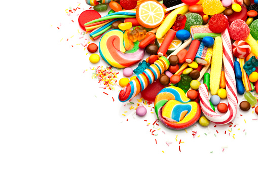 Top view of colorful candies and jellybeans heap arranged at the top corner of a white background leaving a useful copy space for text and/or logo . DSRL studio photo taken with Canon EOS 5D Mk II and Canon EF 100mm f/2.8L Macro IS USM