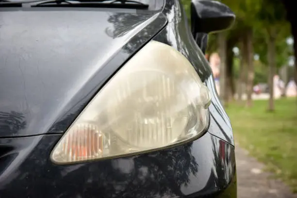 Damaged and blurred headlight surface as a result of weather condition and aging of a car