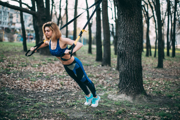 istock Young woman doing suspension training in the park 670131304