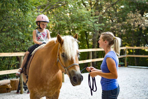 istock Girl Riding Horse In Paddock With Trainer Assisting 670133552