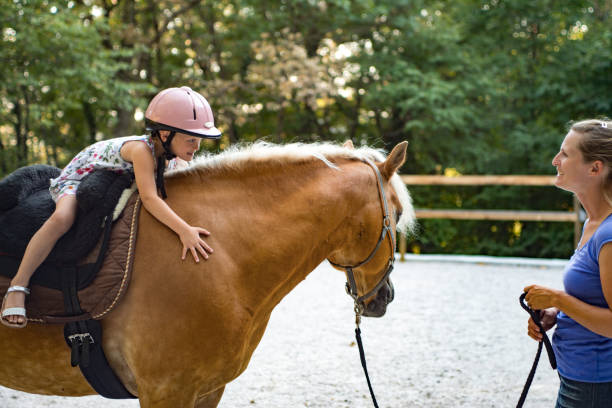 istock Girl Riding Horse In Paddock With Trainer Assisting 670133568