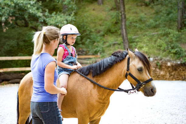 istock Girl Riding Horse In Paddock With Trainer Assisting 670133570