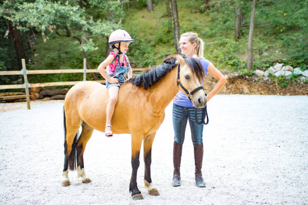 istock Girl Riding Horse In Paddock With Trainer Assisting 670133572