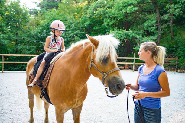 istock Girl Riding Horse In Paddock With Trainer Assisting 670133574