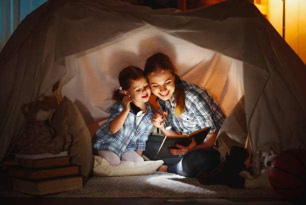 istock mother and child daughter with a book and a flashlight before going to bed 670134346