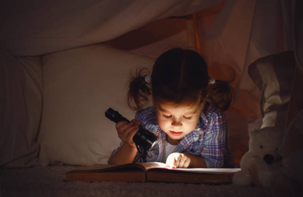 istock child girl with a book and a flashlight and teddy bear before going to bed 670137452