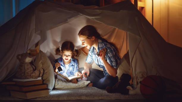 istock mother and child daughter with a book and a flashlight before going to bed 670139846