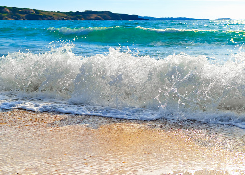 Waves breaking on a sandy beach on the shore of the mediterranean coast