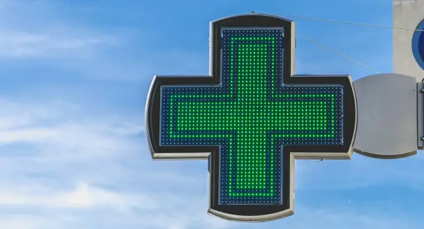 green cross of pharmacy electronics on blue sky