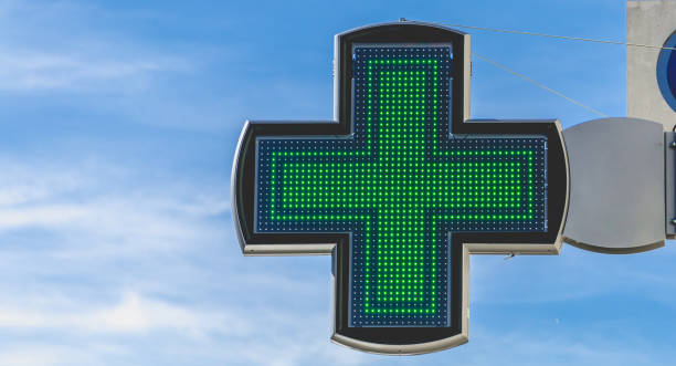 cross of pharmacy electronics on blue sky - green cross imagens e fotografias de stock