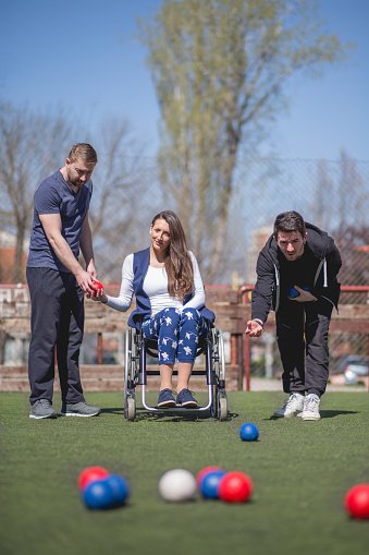 young woman in a wheelchair and his friends are playing boccia
