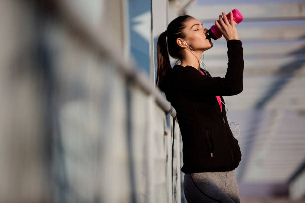 istock Young female drinking water after running 670154548