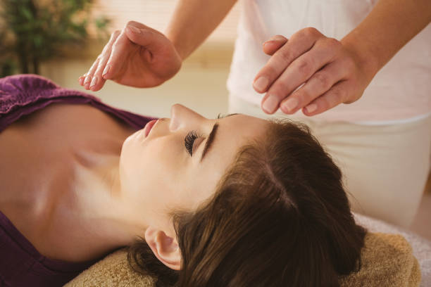 Young woman having a reiki treatment Young woman having a reiki treatment in therapy room reiki photos stock pictures, royalty-free photos & images