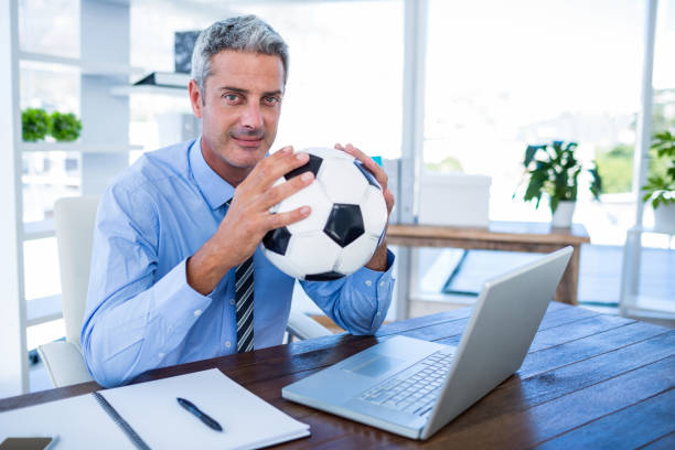 istock Happy businessman looking at camera and holding foot ball 670184018
