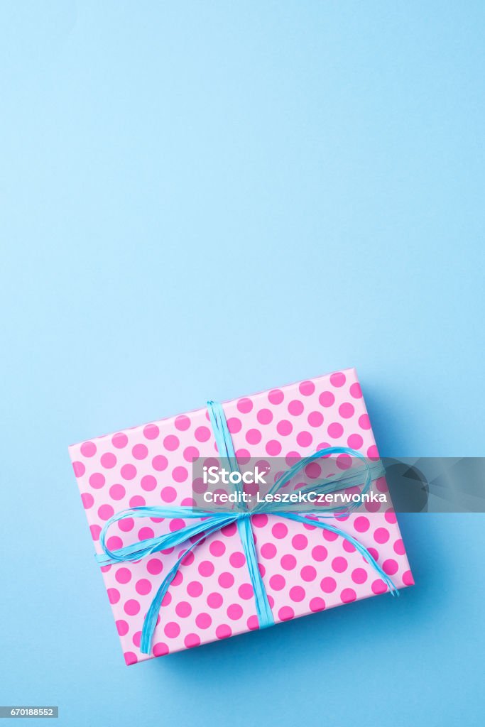 Pink dotted gift box on blue background Pink dotted gift box on blue background. Close up Anniversary Stock Photo