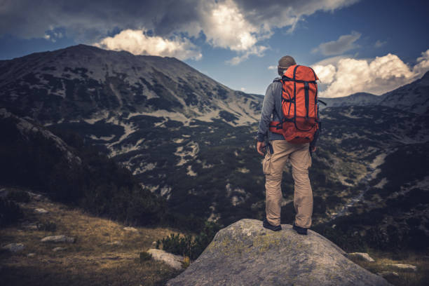 Enjoying majestic mountains and landscape sitting on big rock