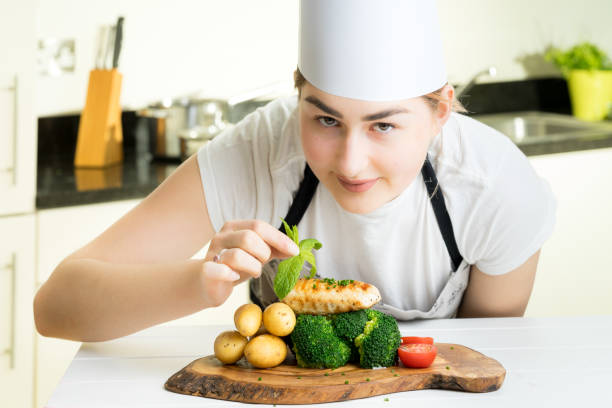 istock female chef garnish chicken vegetable dish kitchen 670195392
