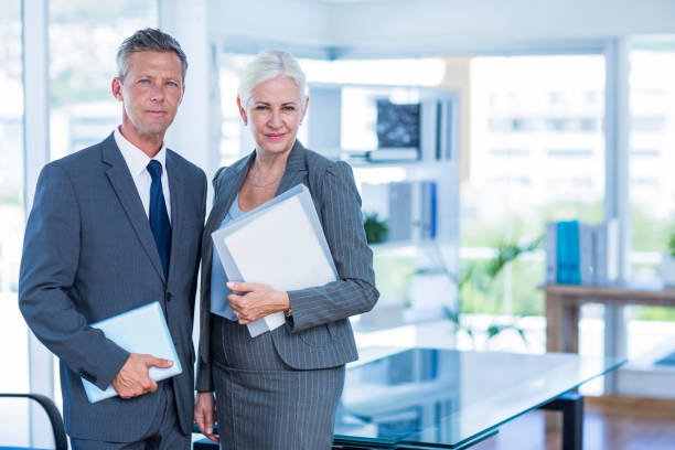 istock Happy business people looking at camera and holding shield 670210070