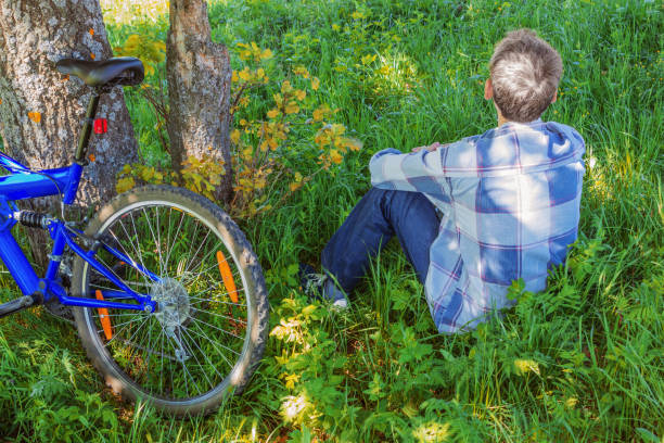 Man  in the green jacket  taking a break from cycling.  Senior man is resting in the city park.Concept of healthy lifestyle and sustainable mobility