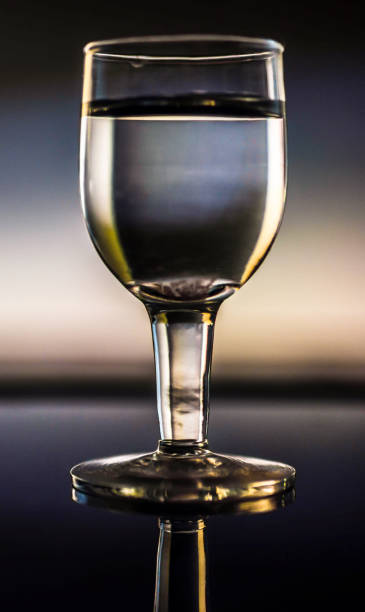 istock Full glass goblet on reflective surface with backlit background - drink, water, drinking, alcohol concept and idea 670216186