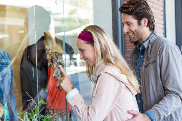 istock Smiling couple going window shopping and pointing at clothes 670217210